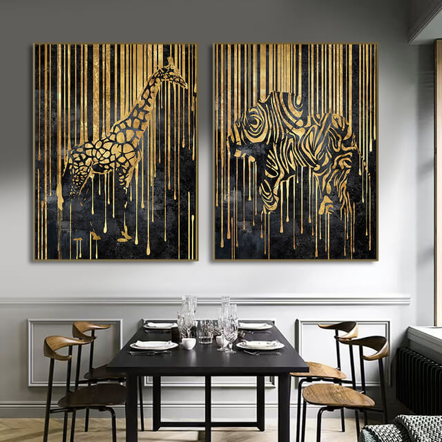 Two canvas prints featuring abstract animal designs, with gold and black colors, displayed on a wall in a dining room setting.