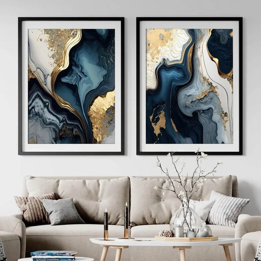 Two framed abstract wall art pieces with navy blue, white, and gold marble designs hanging on a living room wall above a beige sofa.