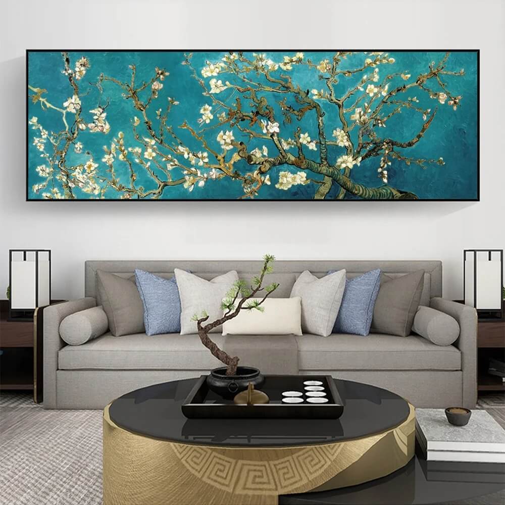 A canvas wall art reproduction of Van Gogh's Almond Blossom hanging above a grey sofa with decorative pillows, a round coffee table, and two lamps on either side.