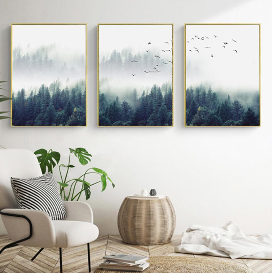 A set of three canvas wall art depicting a Nordic forest scene with fog, displayed above a modern interior setting, unframed.